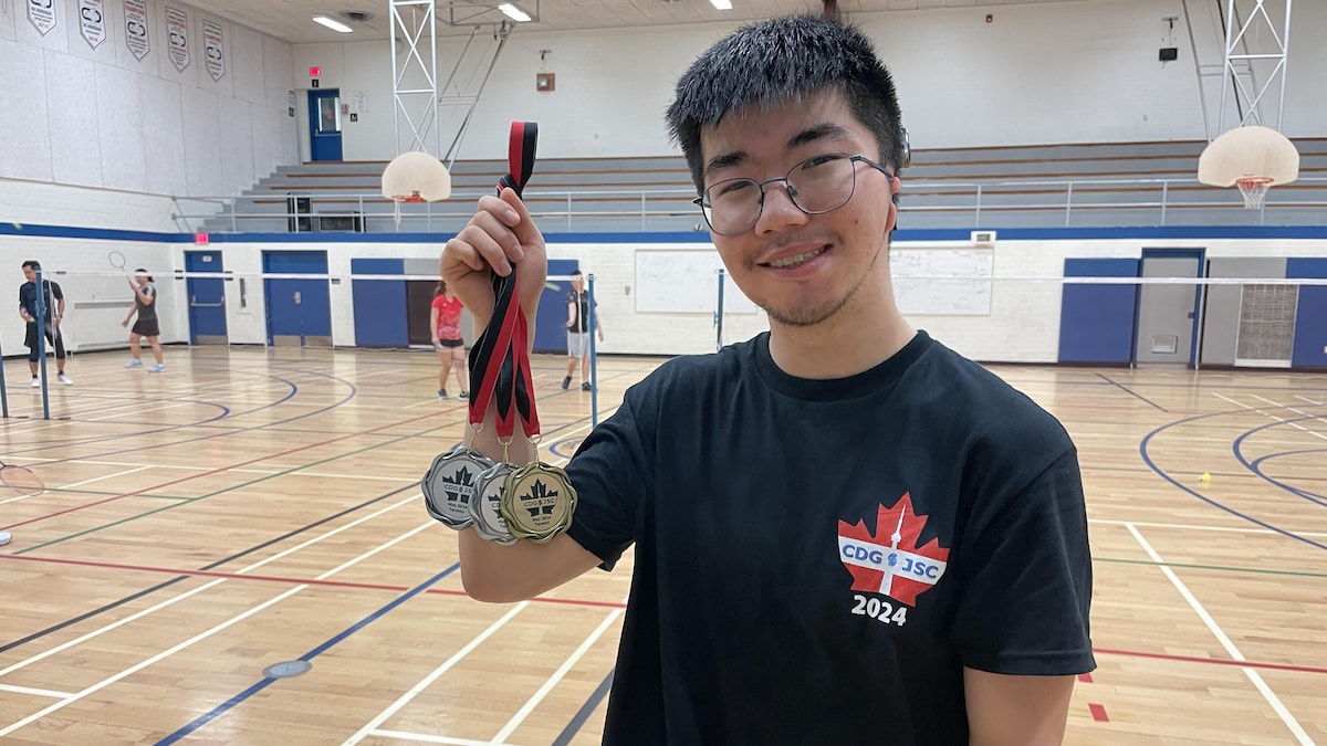 Un joueur de badminton sourd montre fièrement ses médailles remportées aux Jeux du Canada.