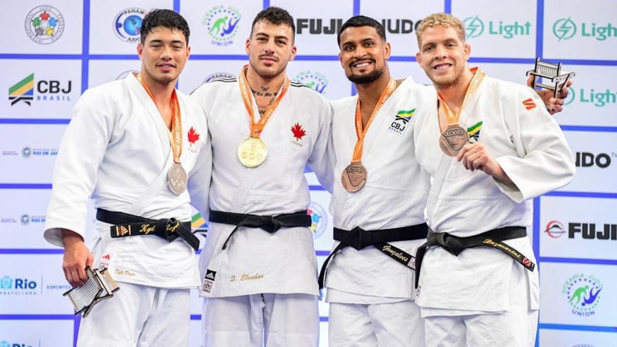 Quatre judokas posent à la caméra avec chacun une médaille.