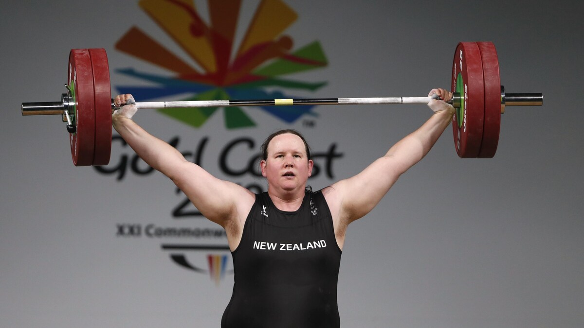 Elle soulève des haltères dans un uniforme noir de la Nouvelle-Zélande.