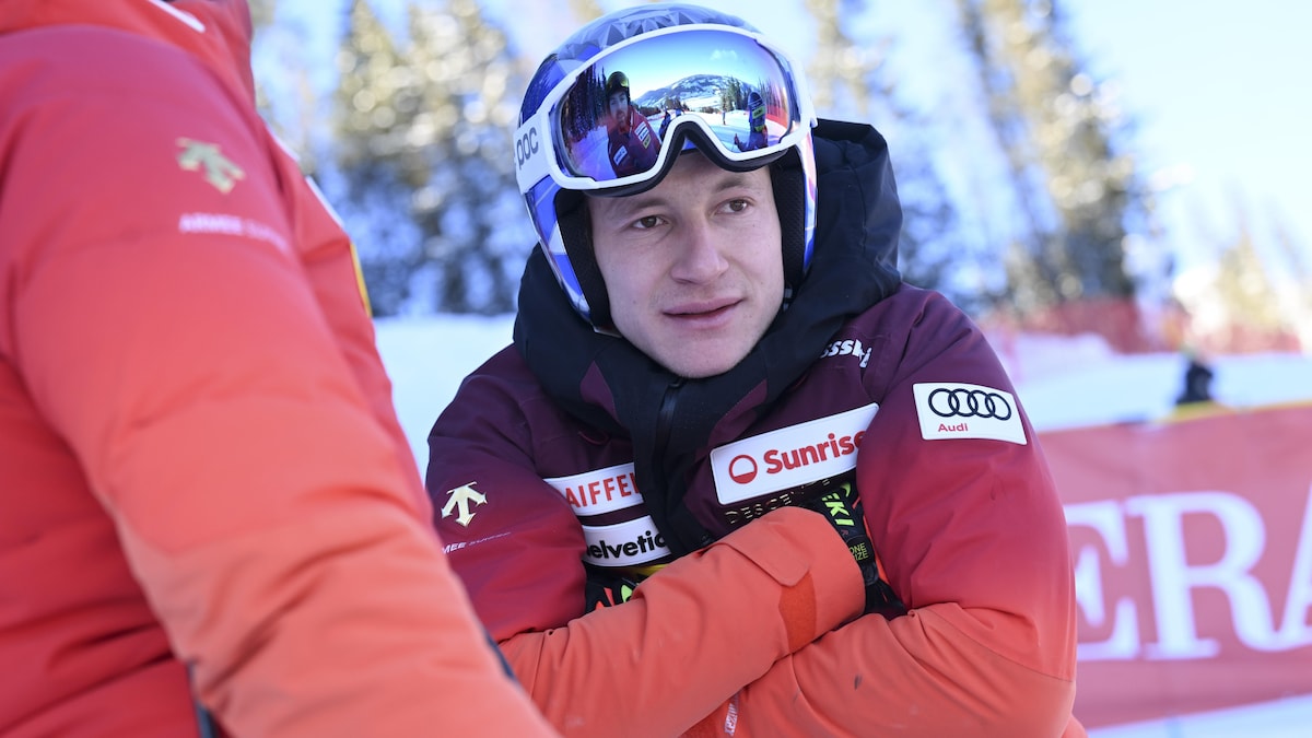 Un skieur pensif a les bras croisés sur ses bâtons et regarde au loin.