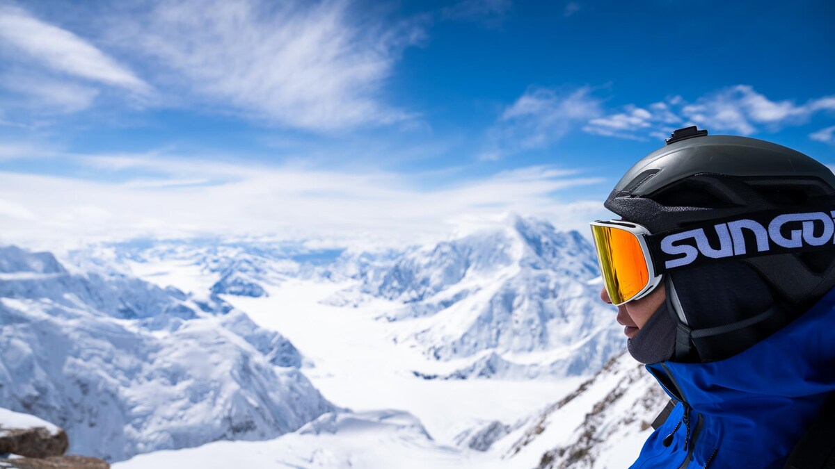 Une alpiniste sur une montagne regarde au loin.