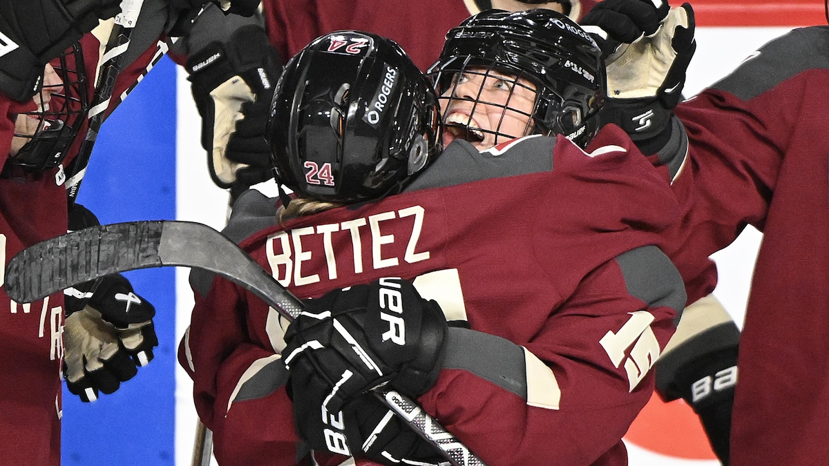 Deux joueuses de hockey se serrent dans leurs bras.