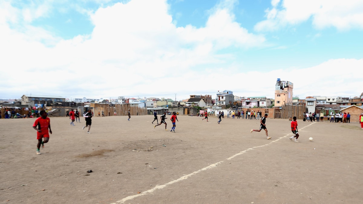 Des enfants jouent au soccer sur le sable.