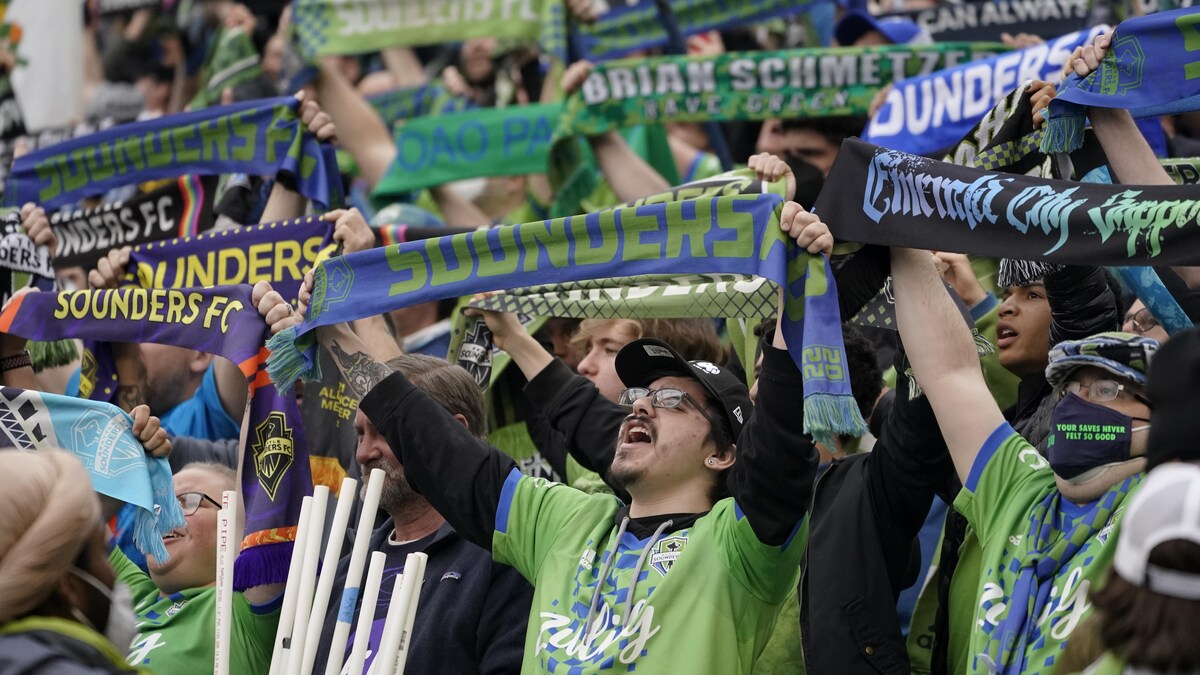 Des supporteurs des Sounders de Seattle brandissent des écharpes du club en encourageant les joueurs.  