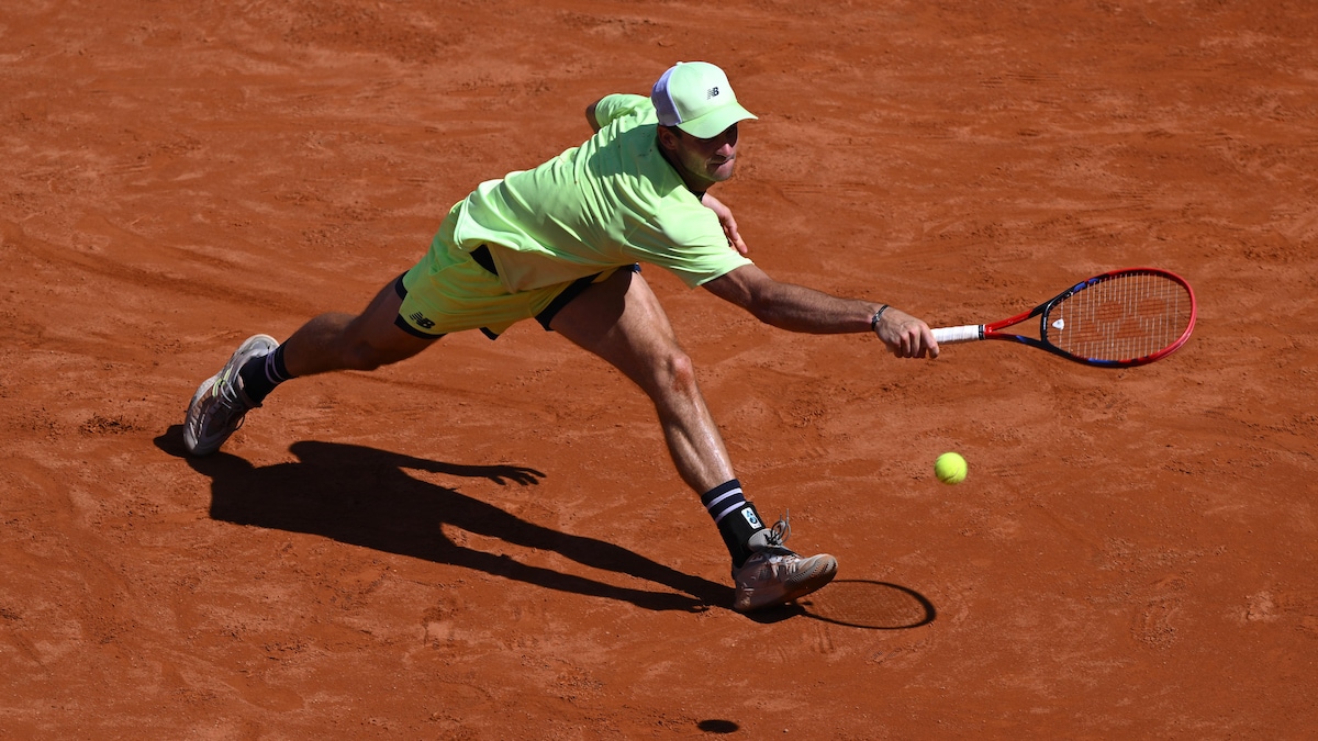 Un joueur de tennis allonge le bras pour frapper la balle du revers.