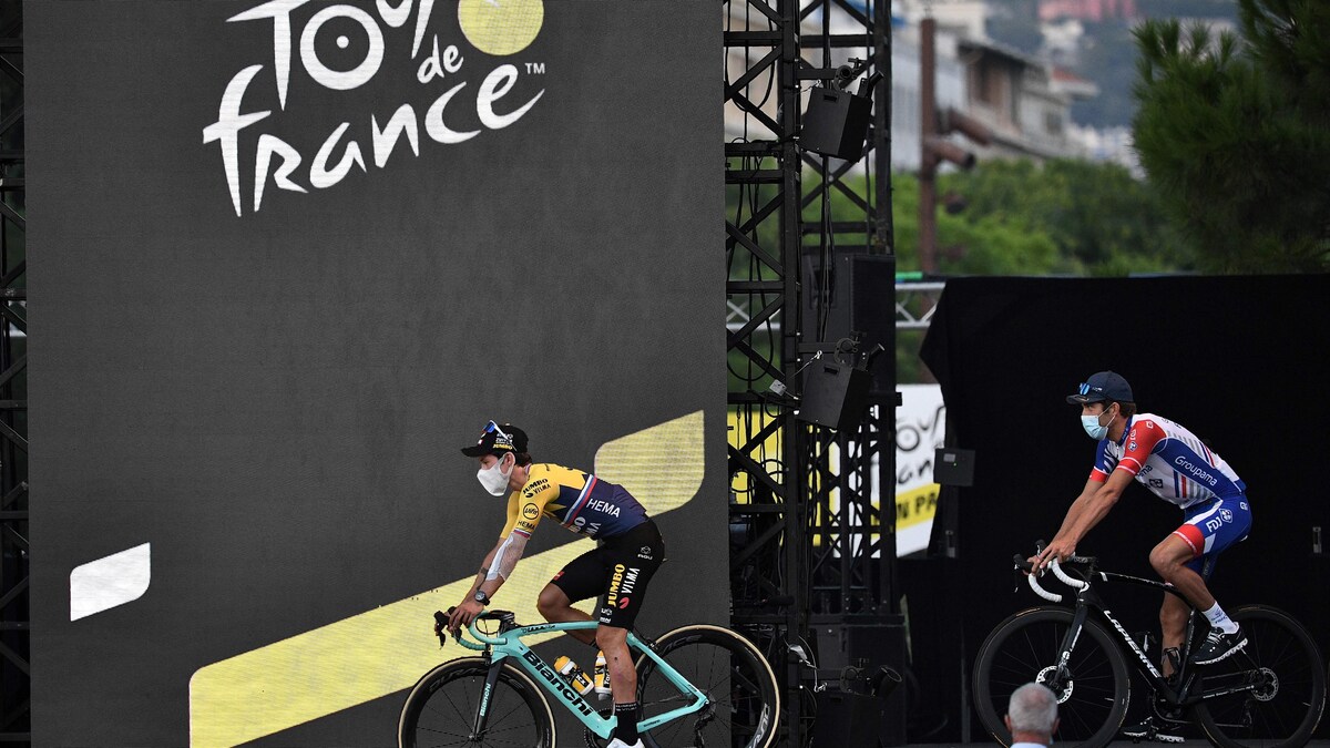 Deux cyclistes portant un masque s'avancent au podium. 