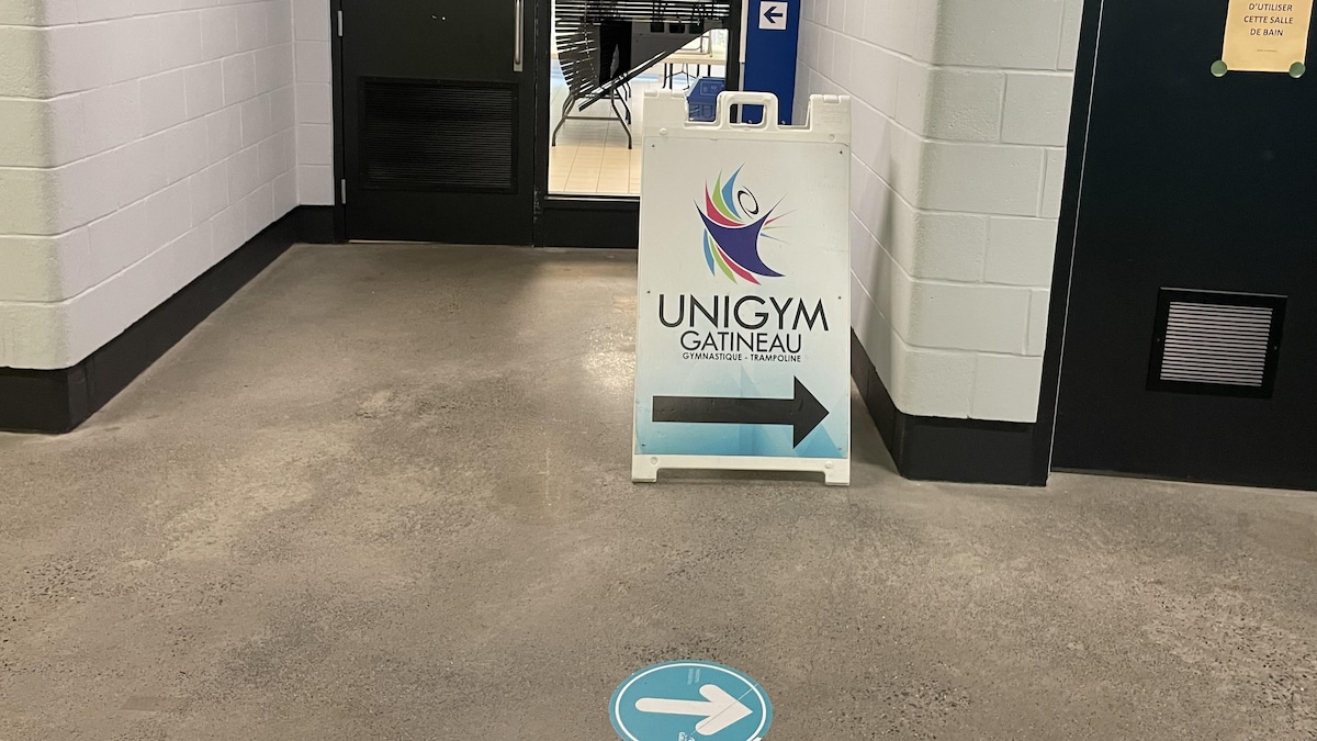 Une pancarte avec un logo de club de gymnastique est installée dans un couloir.
