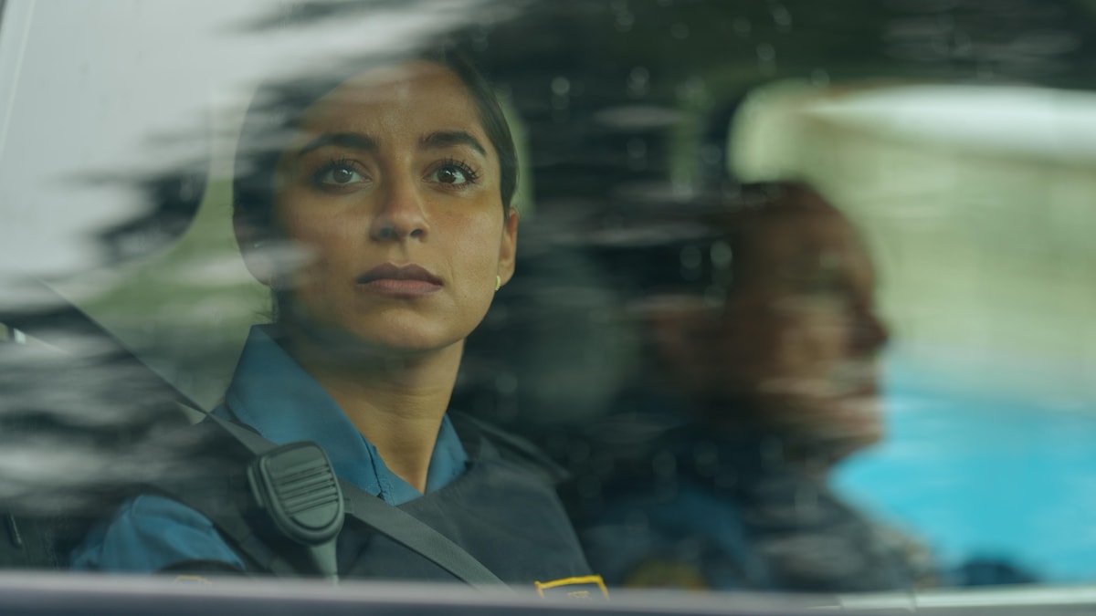 Une femme en uniforme regarde à travers la vitre d'une voiture.