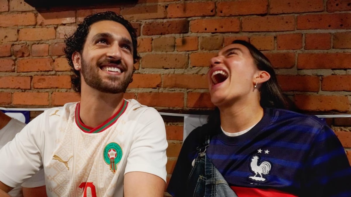Un homme portant les couleurs du Maroc et une femme portant celles de la France rient.