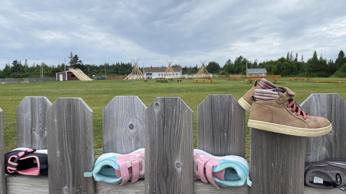 Des chaussures d'enfants accrochées sur une palissade.