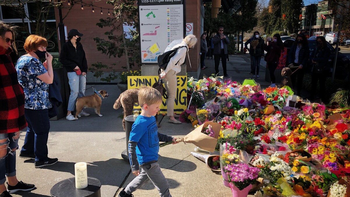 Un garçon dépose des fleurs devant le mémorial pour les victimes de North Vancouver. 