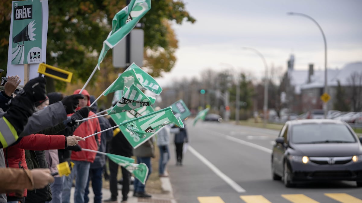 Plusieurs personnes brandissent des pancartes avec l'inscription : En grève.