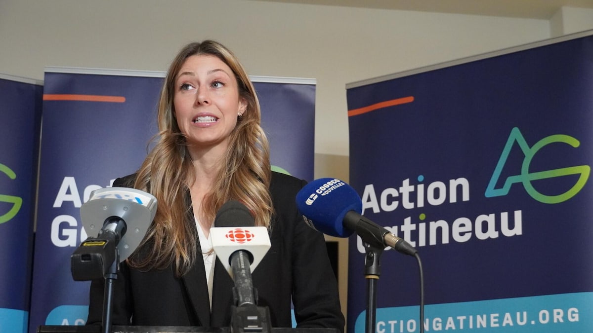 Maude Marquis-Bissonnette s'adresse aux médias devant des banderoles d'Action Gatineau.