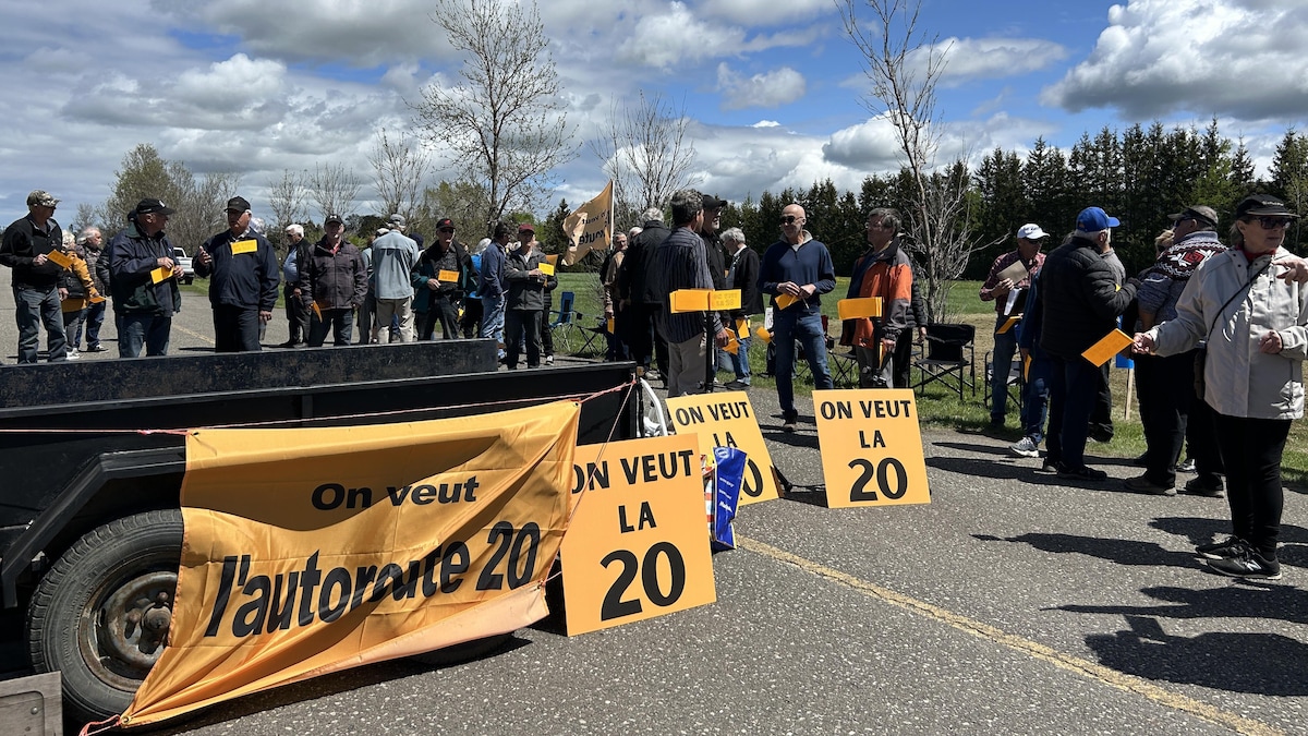 Des groupes de personnes se tiennent à côté de pancartes sur lesquelles est écrit "On veut la 20".