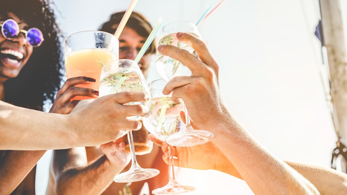 Quatre jeunes adultes soulèvent leur verre pour trinquer. 