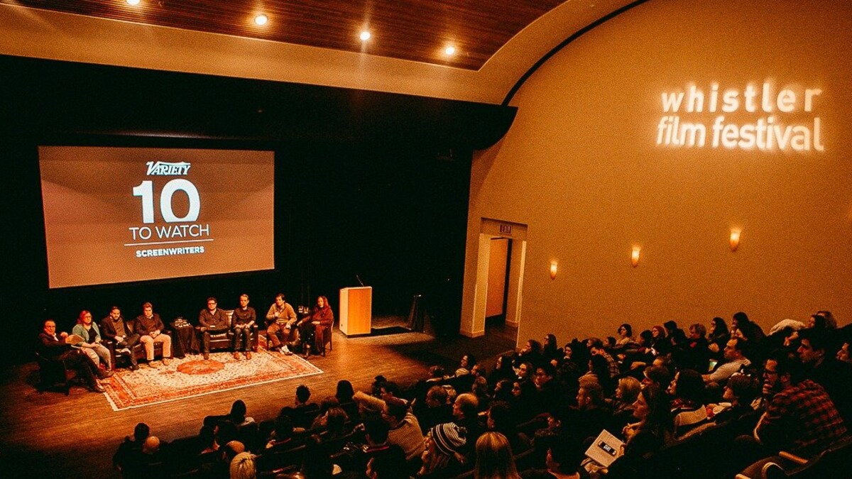 Huit personnes assises sur une scène devant un public au Festival du film de Whistler.