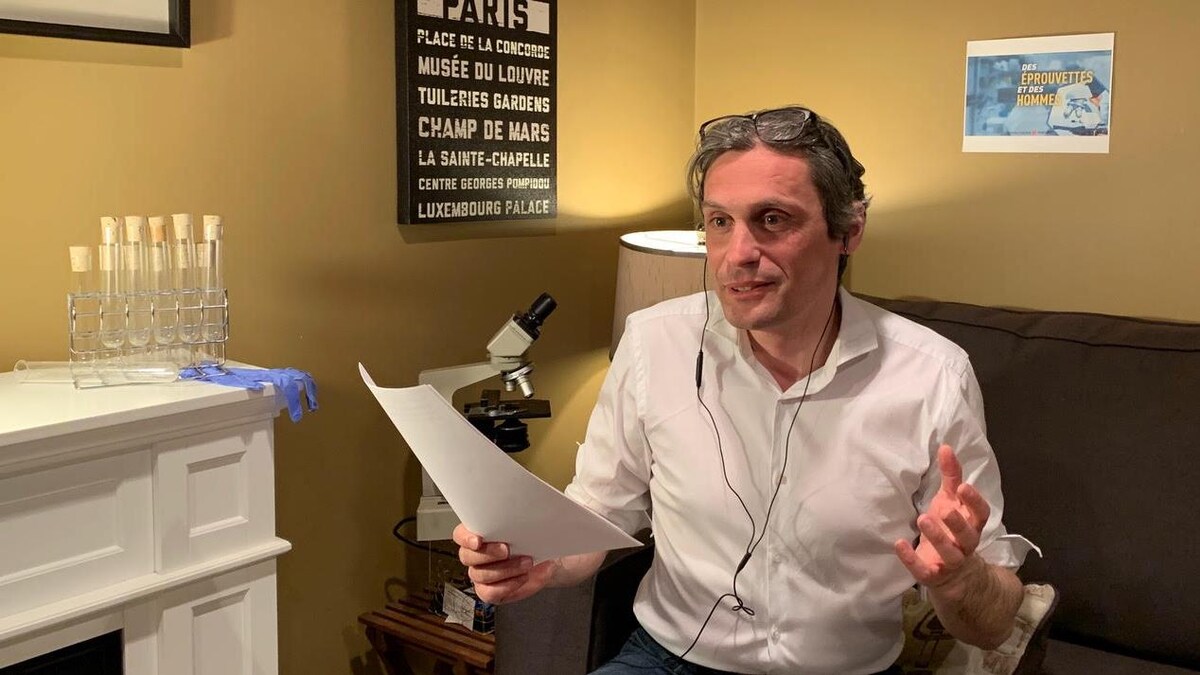 Jean-Eric Ghia est assis sur un canapé, feuilles à la main et écouteurs dans les oreilles.