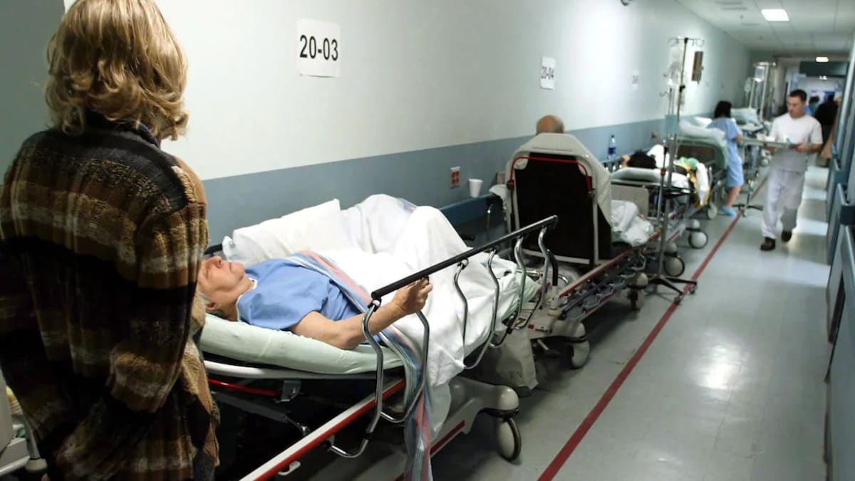 Des patients sur des lits d'hôpitaux dans un couloir.
