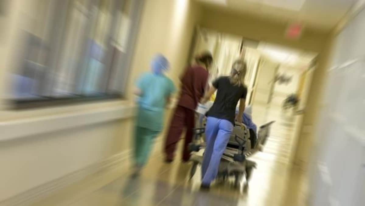 Des infirmières poussent une civière dans un couloir d'hôpital. 