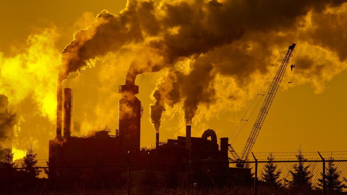 Des installations industrielles et leurs cheminées émettent des nuages importants de fumée.