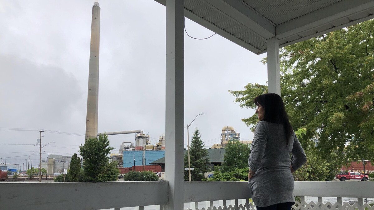 Une femme regarde de son balcon une des cheminées de la Fonderie Horne.