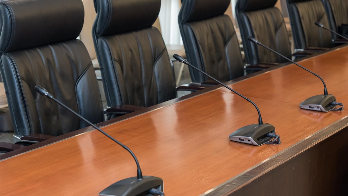 Des micros et des chaises dans une salle de réunion.