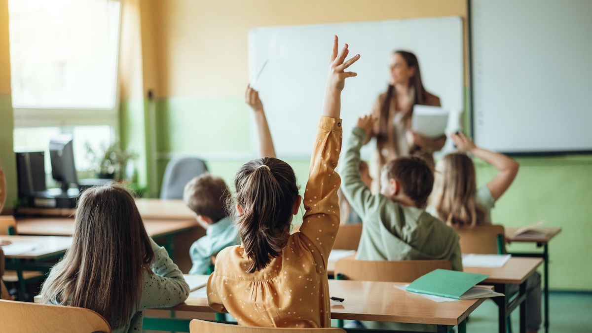 Une élève lève la main en classe.