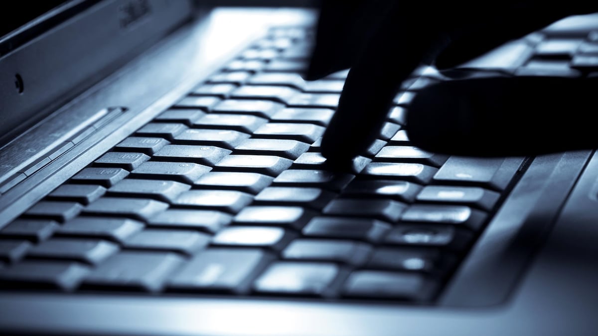 Une personne tape une lettre sur un clavier d'ordinateur.