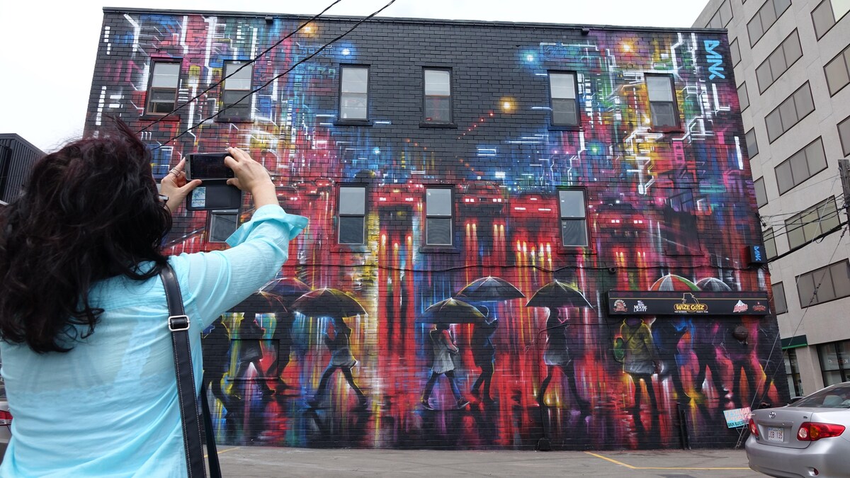 Une femme prend en photo une murale à Moncton, créée dans le cadre du festival Inspire.