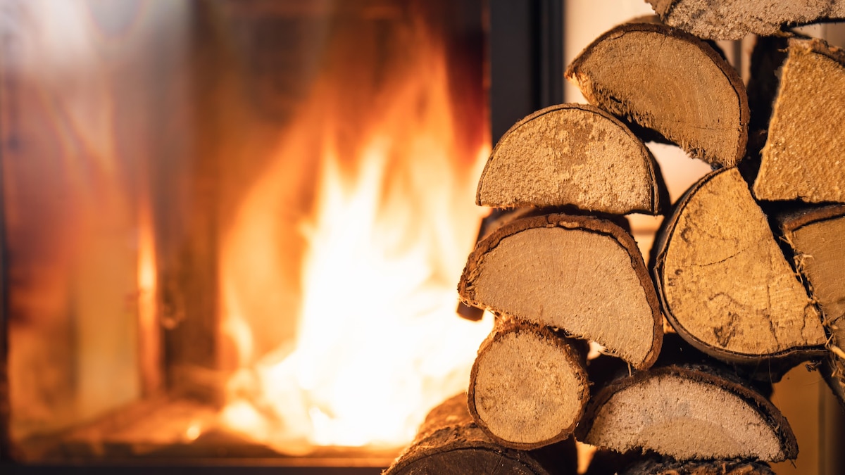 Pile de bois de chauffage devant un poêle.