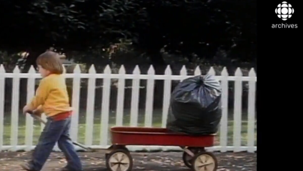 Un enfant tire un chariot qui contient un sac à déchets en plastique.  