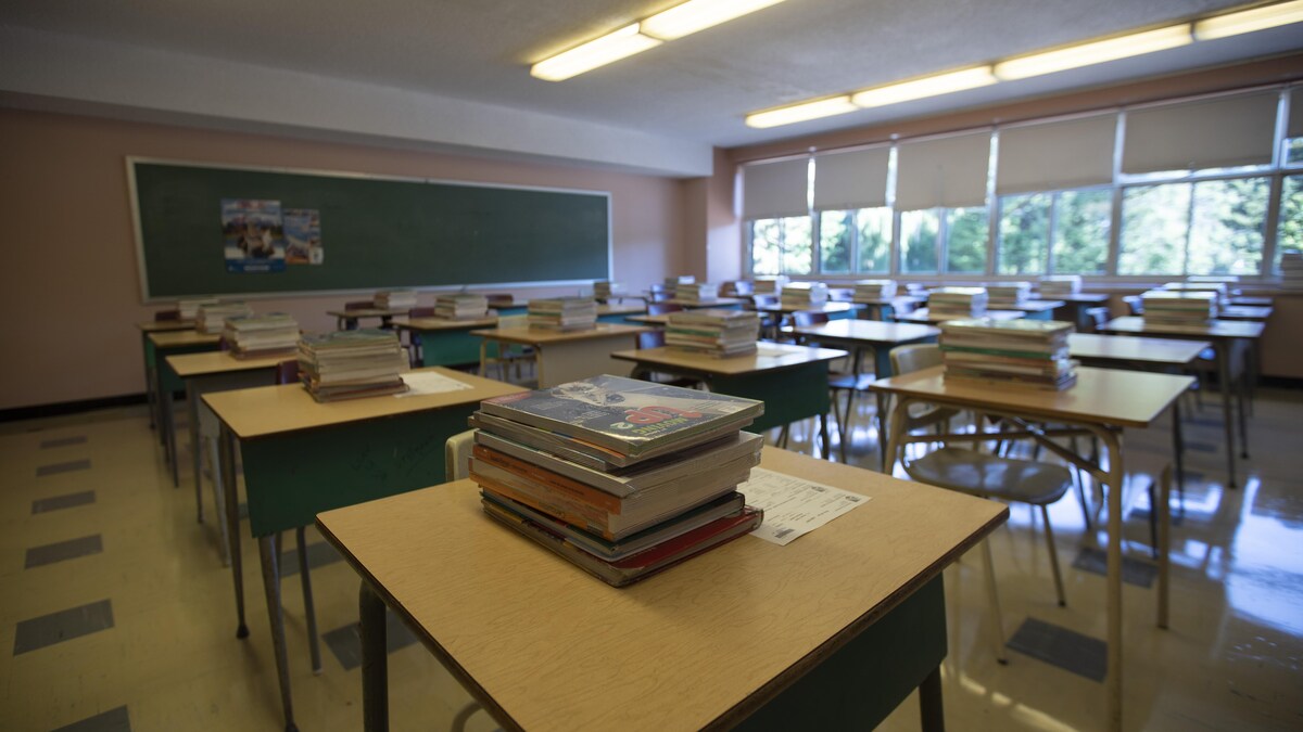 Des livres sont empilés sur des bureaux dans une salle de classe.