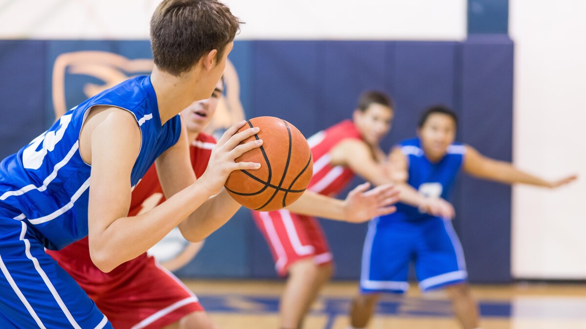 Des adolescents jouent au basketball dans un gymnase.