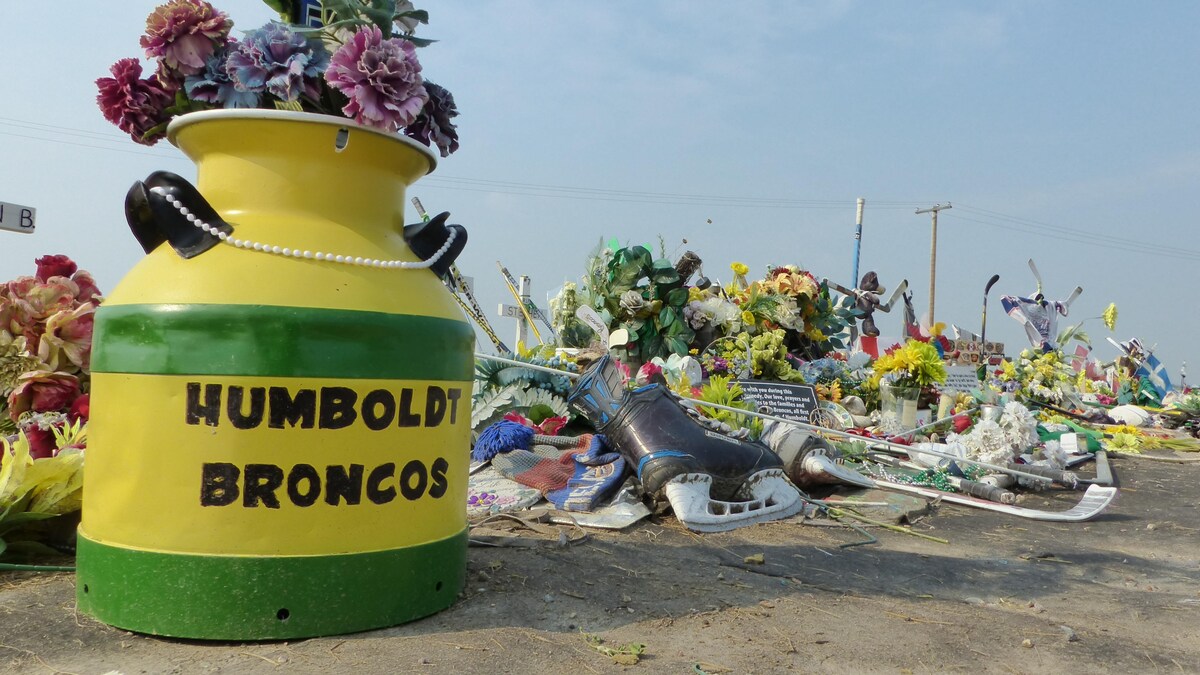 Un pot de fleurs de couleur verte et jaune sur lequel il est écrit : Humbolt Broncos », accompagné de plusieurs objets significatifs, comme des patins à glace. 
