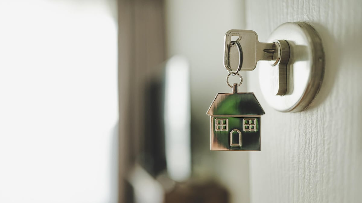 Une clé dans une serrure et un porte- clé représentant une maison.