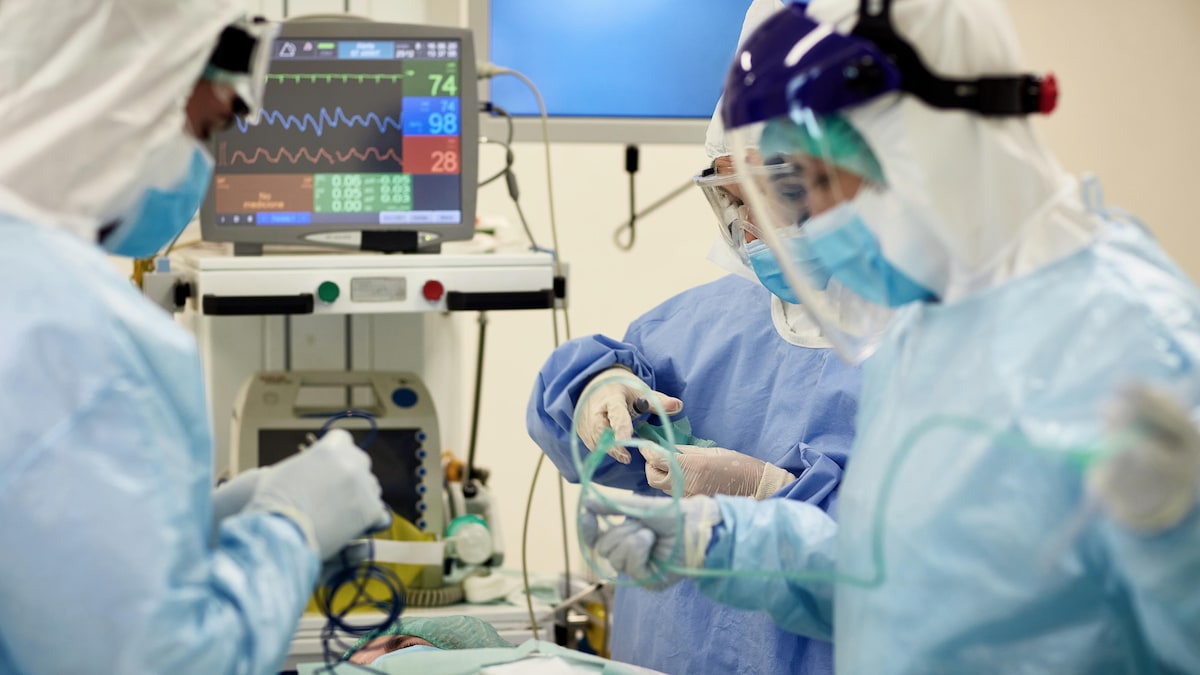 Médecins et infirmières portant des blouses chirurgicales, des lunettes et des masques se préparent à une intervention chirurgicale.