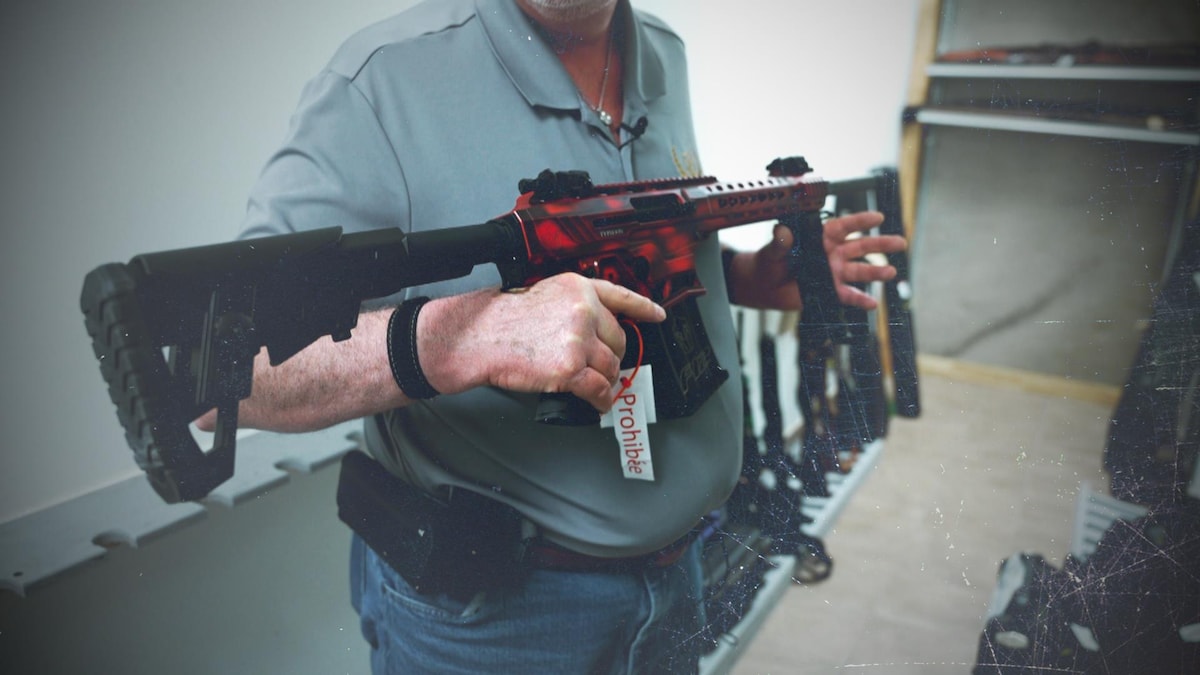 Un homme tient une arme prohibée dans ses mains.