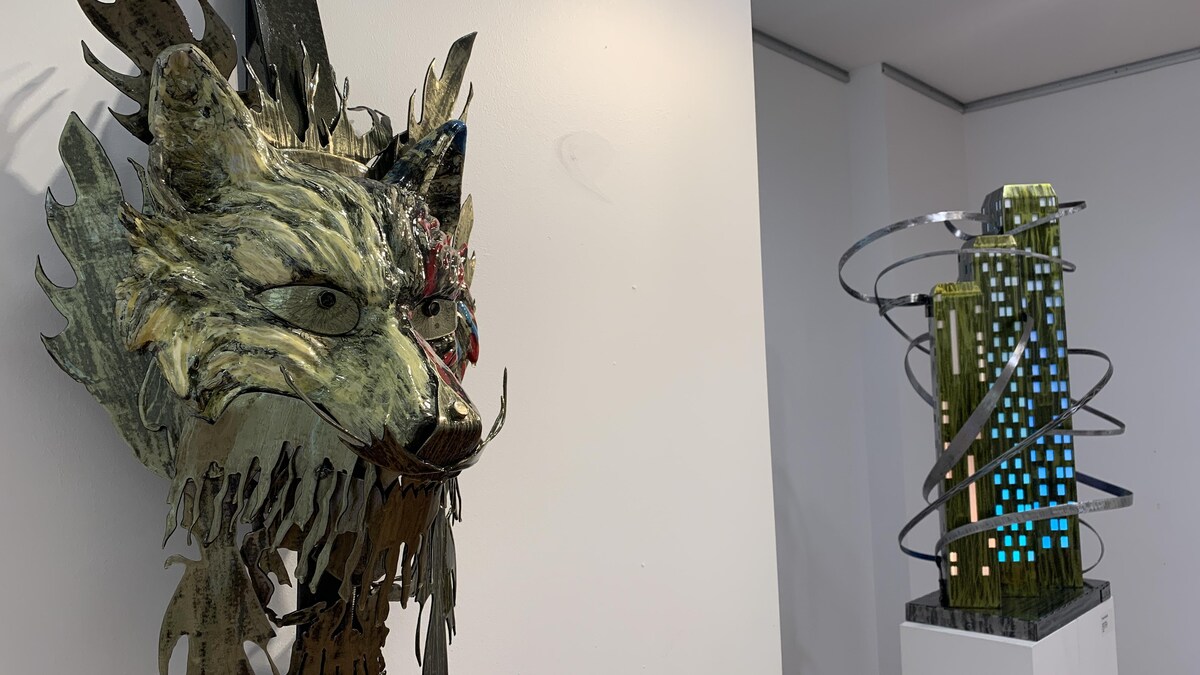 Une sculpture métalique de loup dans une salle d'exposition.