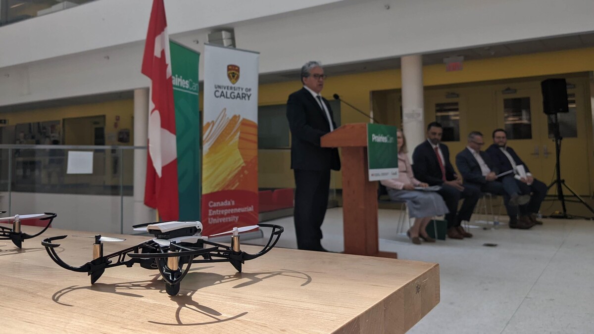 Un drone en premier plan. En arrière-plan, le ministre fédéral Dan Vandal. 