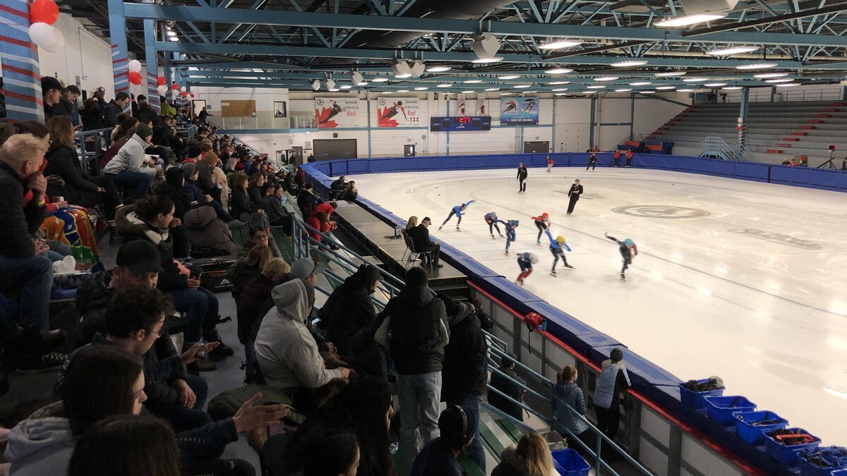 Les spectateurs regardent les patineurs sur la glace à partir des gradins.