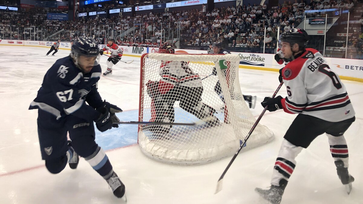 Deux joueurs luttent pour la rondelle derrière le gardien drummondvillois.