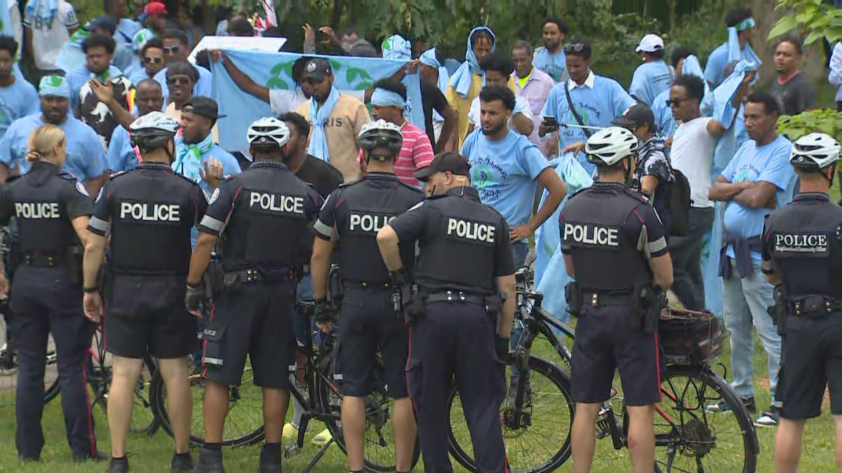 Un rideau de policiers devant un groupe de manifestants.