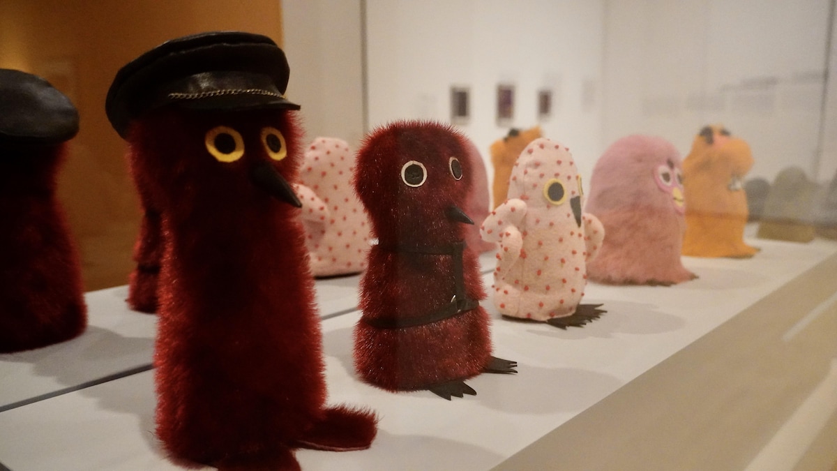 Des œuvres représentant de petites créatures dans une salle d'exposition.