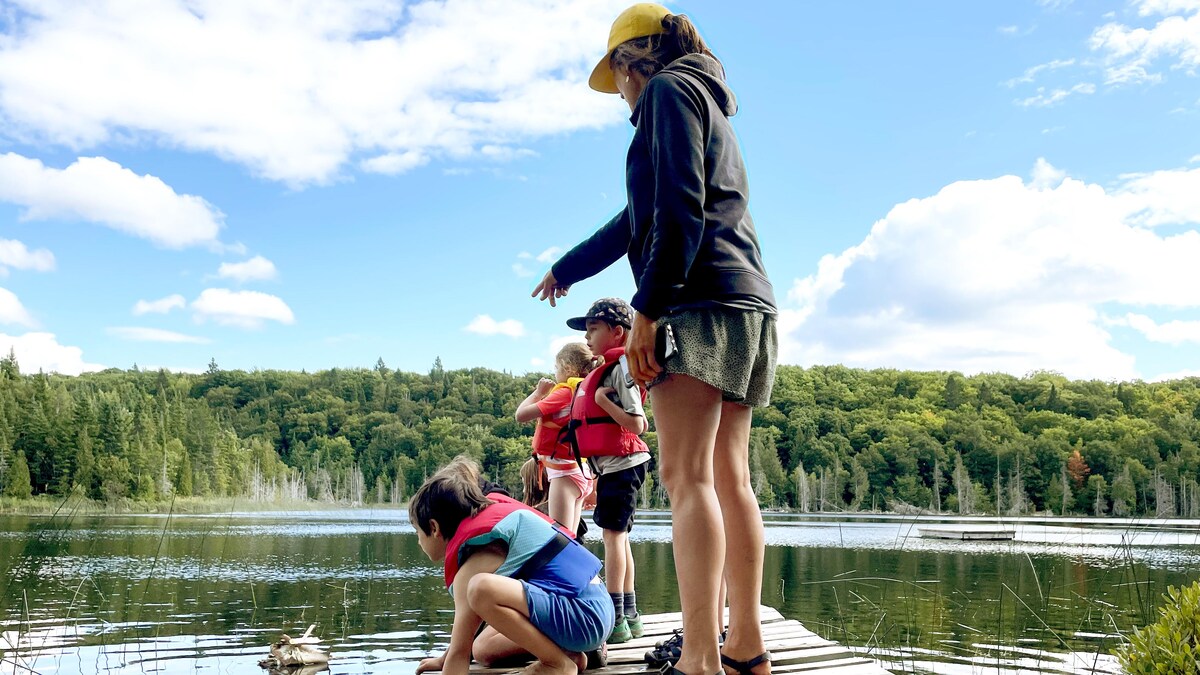 Des bateaux fabriqués à partir de matériaux naturels sont mis à l'eau par les enfants.