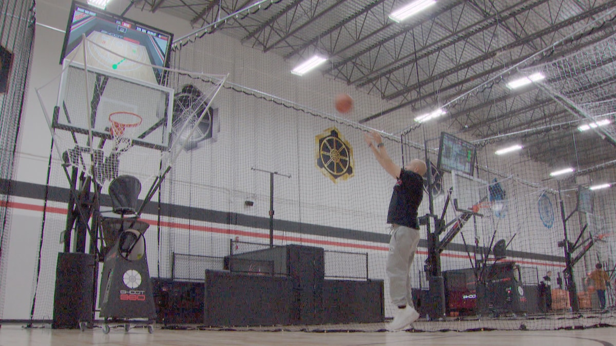 Un homme lance un balon de basketball dans un filet spécial surmonté d'un écran. Mai 2024.