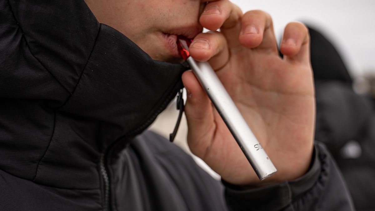 Un jeune avec une vapoteuse à cannabis aux lèvres.