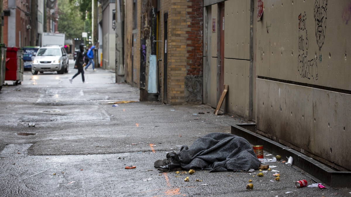 Une personne allongée sous une couverture dans le quartier Downtown Eastside à Vancouver. 