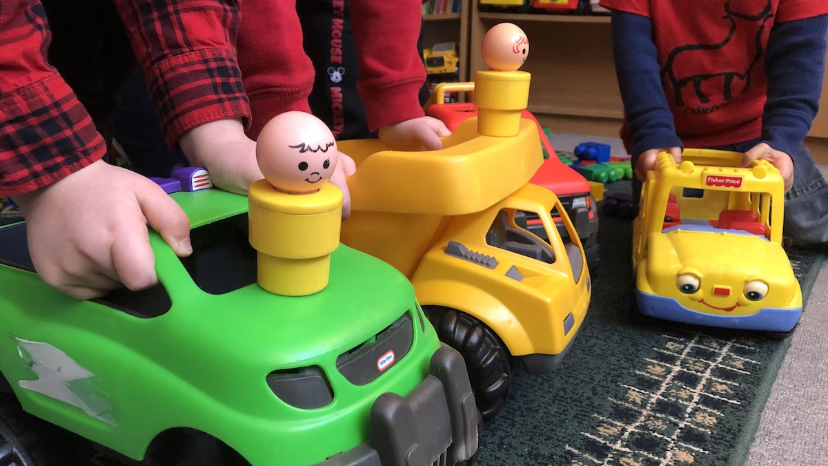 Des bras d'enfants qui jouent avec des camions jouets dans une garderie.
