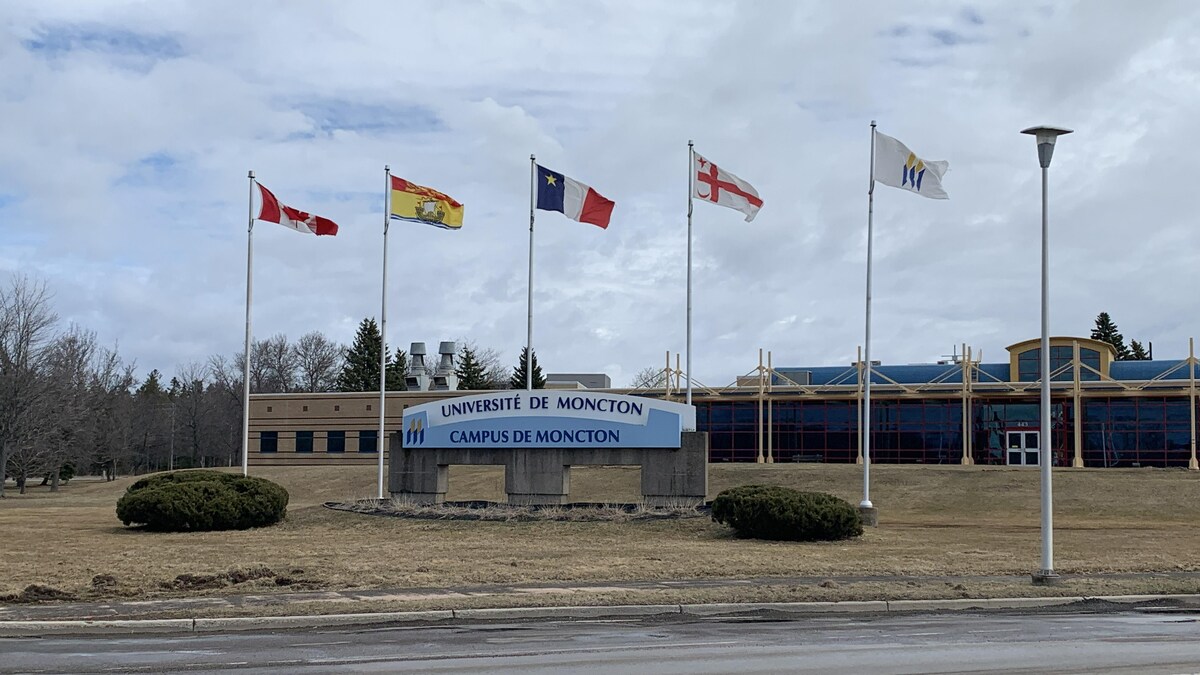L'enseigne du campus devant les drapeaux du Canada, du Nouveau-Brunswick, de l'Acadie et du Grand conseil mi'kmaq.