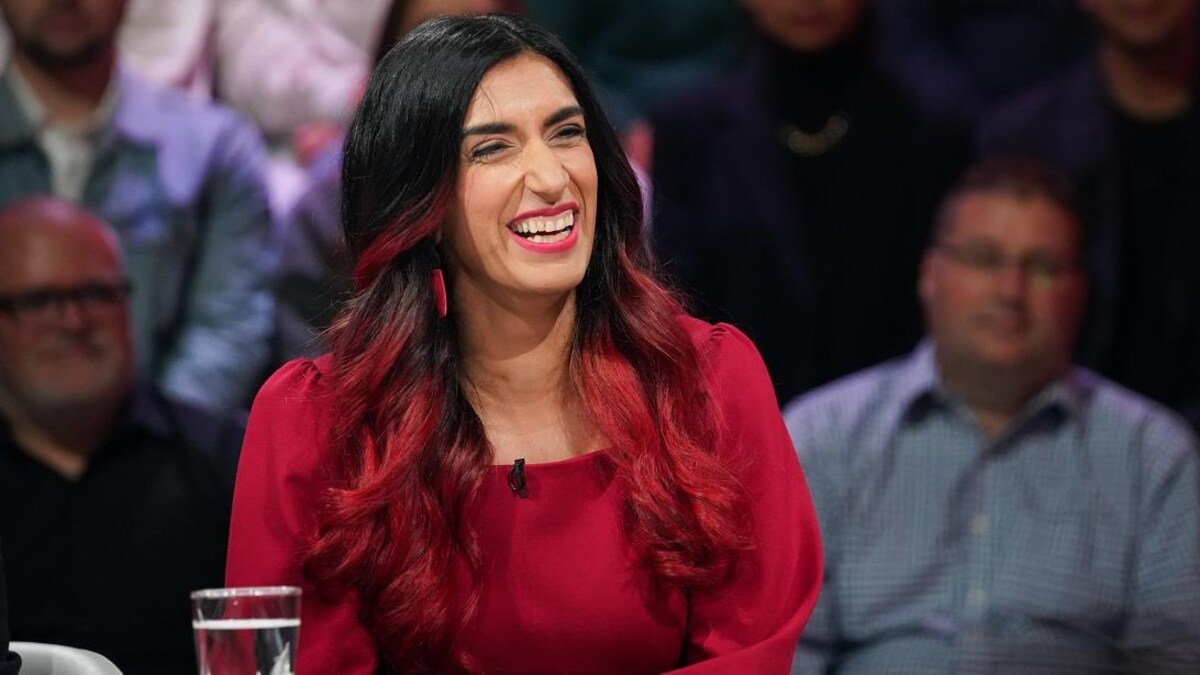 Une femme qui sourit. Elle a des mèches rouges dans ses cheveux bruns.